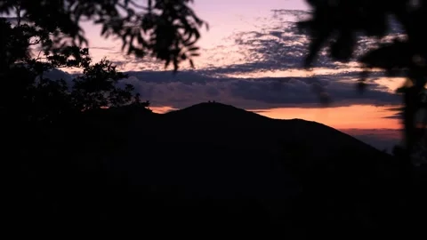 Silhouetted Mountain Range at Dusk with Vibrant Purple, Pink, and Orange Sun Stock Footage 314703645
