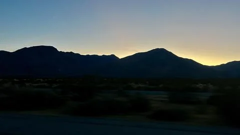 Silhouetted mountain range at sunset, or sunrise, with golden sky gradient Foto stock