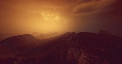 Silhouetted mountains at dusk under a dramatic sky with warm hues Illustrazione stock