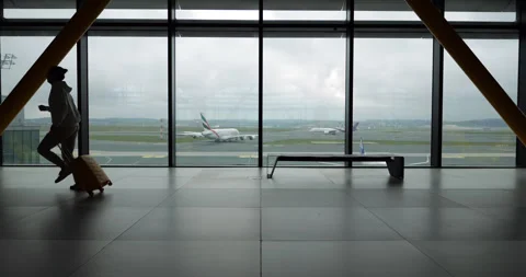 Silhouetted passenger rushing through empty airport terminal to catch flight Stock Footage 345553410