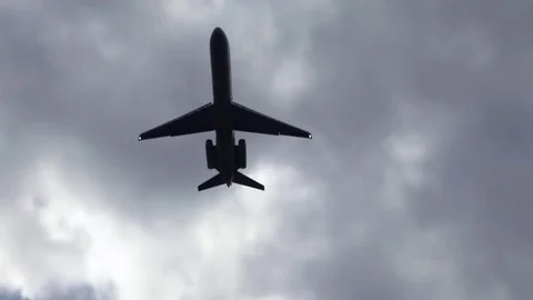 Silhouetted plane takes off overhead, in front of a dramatic cloudscape Stock Footage 80439987