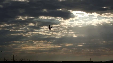 Silhouetted plane takes off overhead, in front of a dramatic cloudscape Stock Footage 80439991