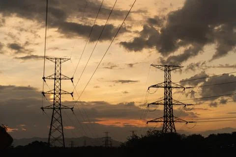 Silhouetted Power Lines Against Dramatic Sunset Sky with Wispy Clouds and W.. Stock Photos