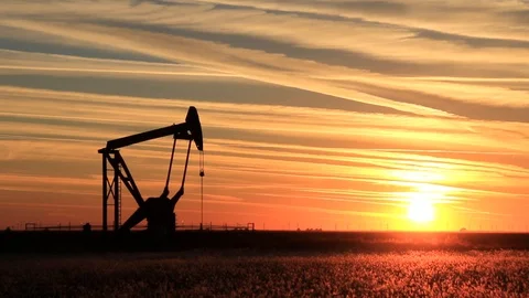 Silhouetted pumpjack in the oil field at sunset Stock Footage 127597973
