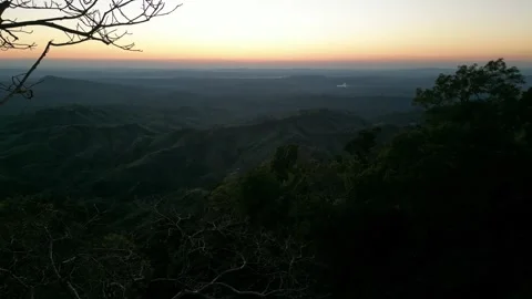 Silhouetted tree branches overlooking layered mountain valley at golden sun.. Vídeo Stock 345089051