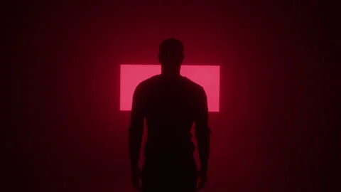 Silhouetted View of Man Standing in Dark Room in Front of Projecting Symbols Stock Footage 208801083