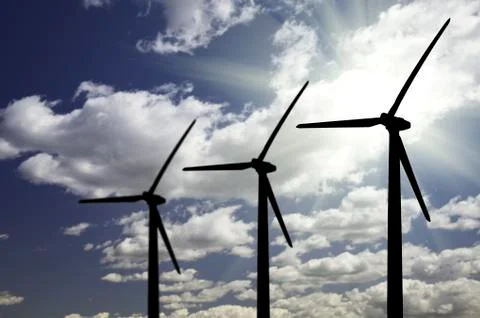 Silhouetted Wind Turbines Over Dramatic Sky and Clouds. Stock Photos