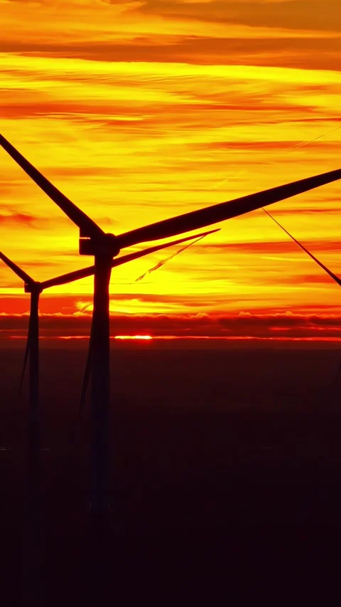 Silhouetted Wind Turbines Spin at Sunset Beneath Dramatic Orange Sky Outdoors Stock Footage 336237527