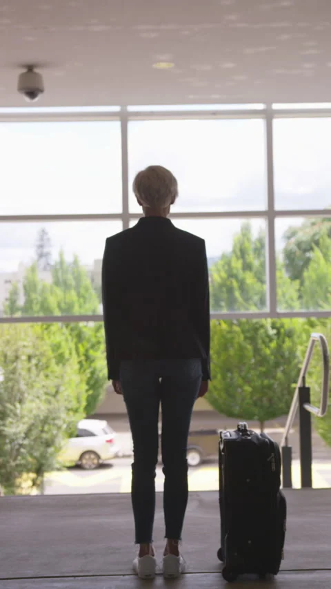 Silhouetted Woman with Pixie Cut and Suitcase Looking Away Toward Street Stock Footage 208778516