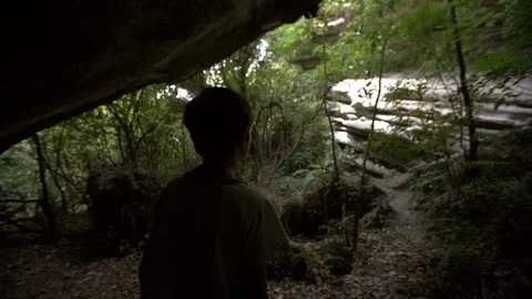 Silhouetted Young Boy Looking out of Cave Stock Footage 98678583