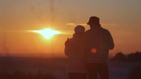 Silhouettes of affectionate couple hugging and kissing at winter sunset Video stock 327929674