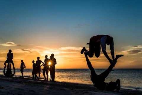 Silhouettes of African men dancing on the beach at sunset 写真素材