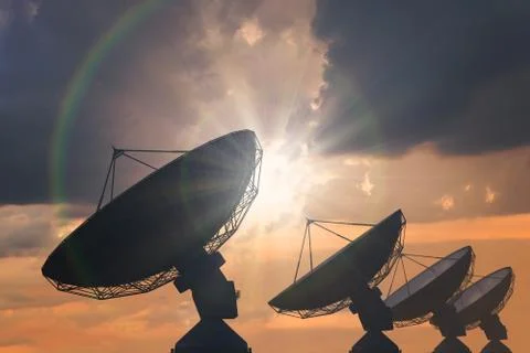 Silhouettes of array of satellite dishes or radio antennas at sunset. Stock-Fotos