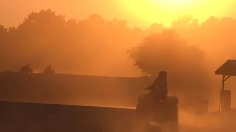 Silhouettes of ATVs Riding by a Pond-side Shack in the Dust at Sunset - 4k Vídeos de archivo 239671860