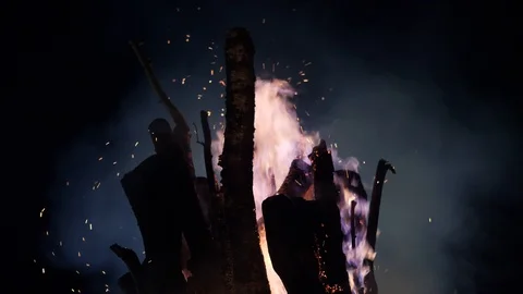 Silhouettes of campfire logs, fire flames and sparkles against dark sky. Low Stock Footage 116777873