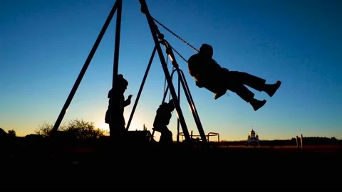 Silhouettes of children on a swing 4K Video stock 99263252