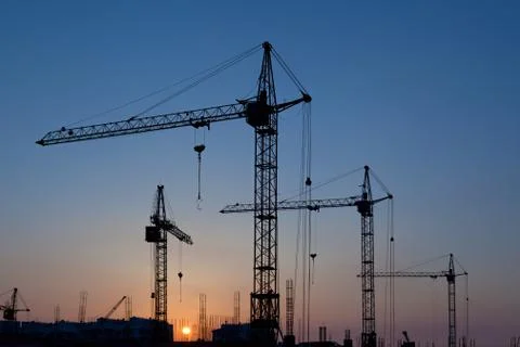 Silhouettes of construction cranes Stock Photos