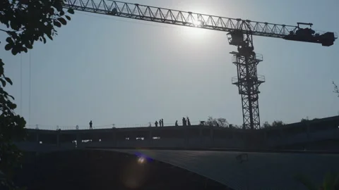 Silhouettes of construction workers and crane at sunset on building site Stock Footage 332397634