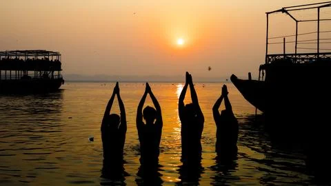 Silhouettes of devotees praying in holy ganges river during chhath festival.. Stock Photos