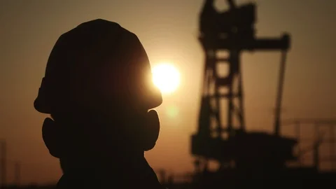 Silhouettes of engineer at oil rig pump of petrochemical industry in sunset sky Stock Footage 99659743