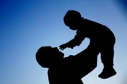 Silhouettes of father and baby son which are playing Stock Photos