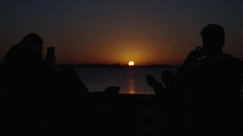 Silhouettes filming the sunset with the mobile Stock Footage 170728212