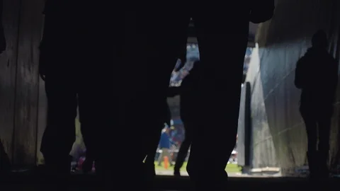 Silhouettes of football players and personnel walking down the tunnel Stock Footage