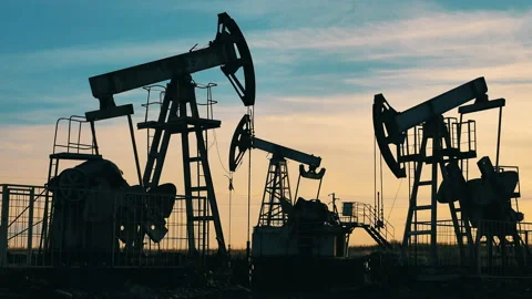 Silhouettes of functioning oil pumpjacks at sunset Stock Footage 144097858
