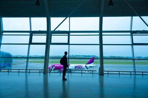 Silhouettes of a guy looking at the plane through the huge window of the airp Stock Photos