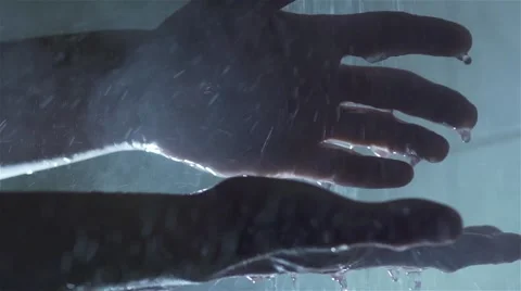 Silhouettes of male hands of nearly flooded with clean water to slow motion Stock Footage