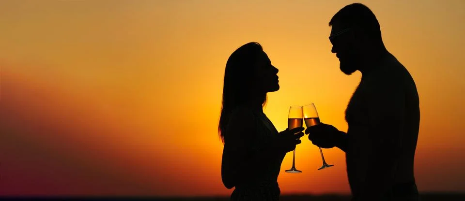Silhouettes of man and woman at sunset dramatic sky background, couple toasti Stock Photos