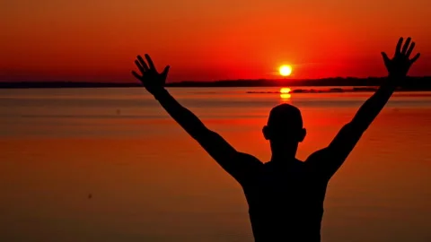 Silhouettes of a Man with Raised Hands at Sunset Alone Stock Footage 252798809