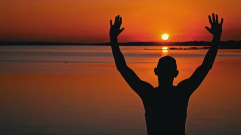Silhouettes of a Man with Raised Hands at Sunset Alone Vídeo Stock 252800360