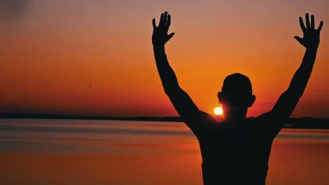 Silhouettes of a Man with Raised Hands at Sunset Alone Stock Footage 252800498