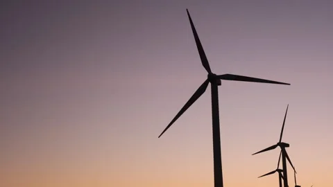 Silhouettes of modern wind turbines with rotating blades against a colorful Vidéo 345840021