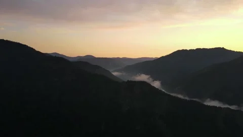 Silhouettes of mountains against the backdrop of the setting sun. Aerial Stock Footage 168416965