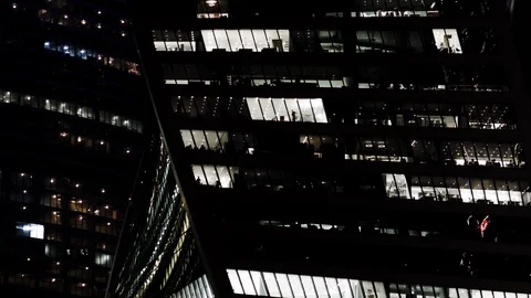 Silhouettes of office workers seen in the windows of an office building Stock Footage 96587492