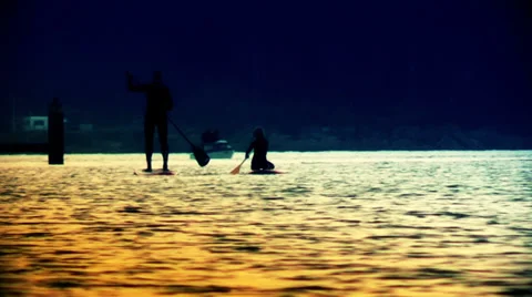 Silhouettes paddling on a river at sunset Video stock 35311836