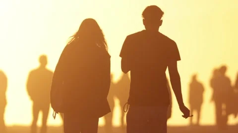 Silhouettes of people in the bright light of sunset - a couple walking forwards Stock Footage 237712590
