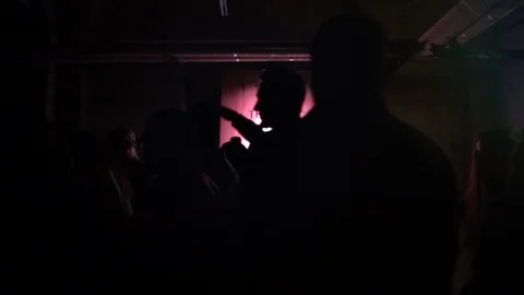 Silhouettes of people dancing in dark basement night club with lens flare Stock Footage 107633432