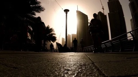 Silhouettes of people engaged in walking and Jogging in Dubai Marina at sunset Stock Footage