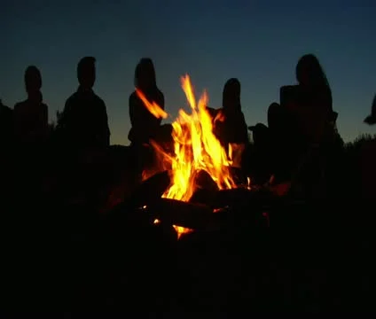 Silhouettes of people sitting around campfire Stock Footage