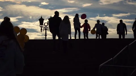 Silhouettes of people walking upstairs and downstairs against evening sky. Slow Stock Footage
