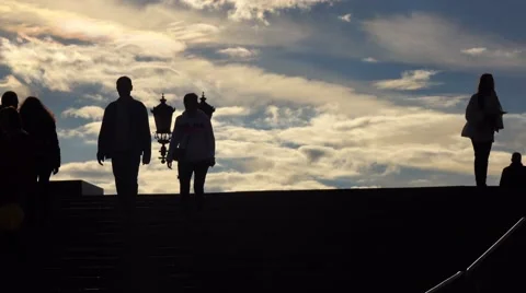 Silhouettes of people walking upstairs and downstairs against evening sky Stock Footage