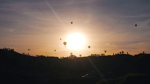 Silhouettes of people watching air balloons show at the sunset Stock Footage