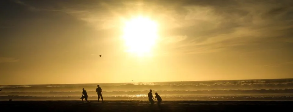 Silhouettes Playing Football on Beach Stock Photos