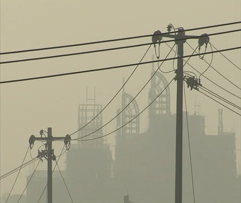 Silhouettes of power lines and skyscraper construction seen through smog Stock Footage 86744146
