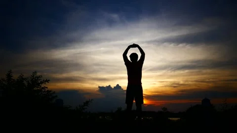 Silhouettes of relax man with the background of the sunset sky Stock Footage 160560574