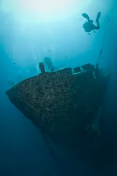 Silhouettes of scuba divers exploring the bow of a shipwreck. red sea, egypt. Stock Photos