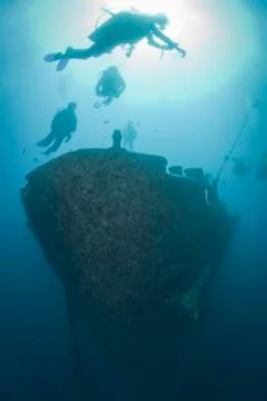 Silhouettes of scuba divers exploring the bow of a shipwreck. red sea, egypt. 库存照片